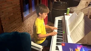Piano Student Valentino Pellegrino from Marbella, practicing behind his white baby grand, showcasing Children's Piano Lessons Marbella