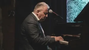 Adult piano lessons marbella student, practising behind the grand piano on stage