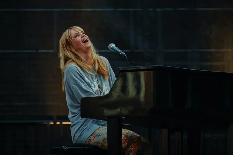 Adult piano student performing live while singing and playing grand piano on stage, showcasing piano lessons for adults in Marbella