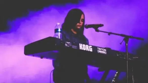 Piano lessons for singers Marbella – vocalist performing live while playing keyboard and singing on stage.