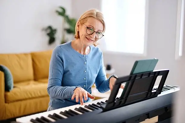 Adult piano student practising at her piano at home, appearing in the article: What adult piano students learn.